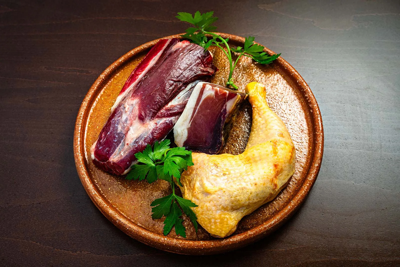 Zancarrón de novilla tudanca y muslo de pollo con perejil, en plato de barro