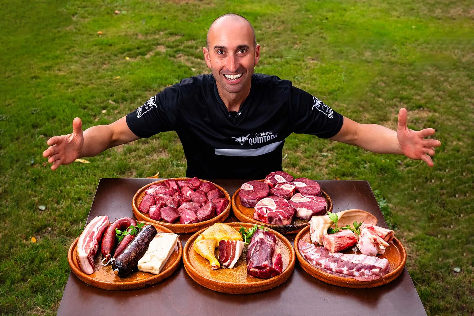 Manuel Quintana con los brazos abiertos detrás de una mesa con la carne para cocido y guisos del pack